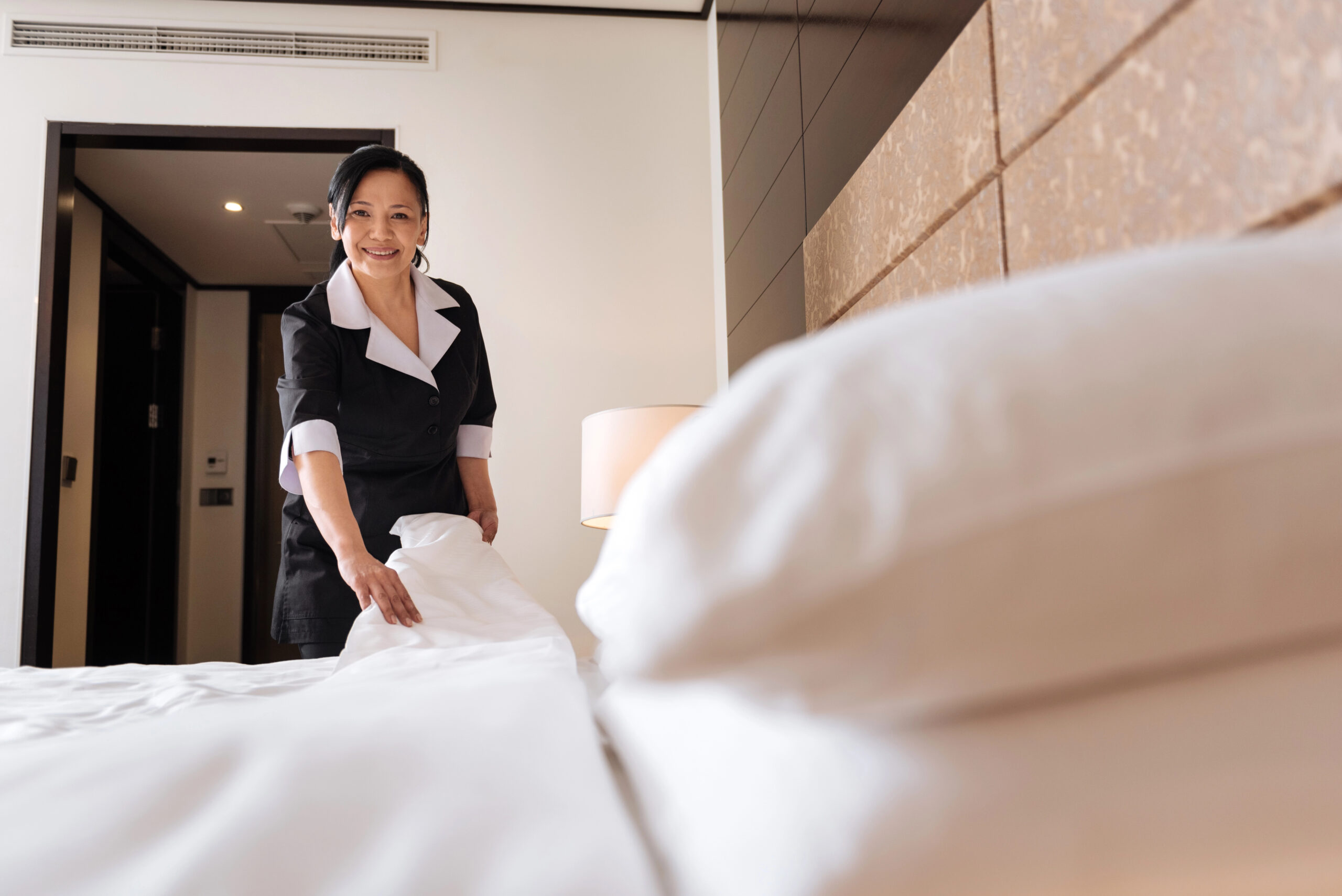Hotelangestellte macht ein Bett im Gästezimmer