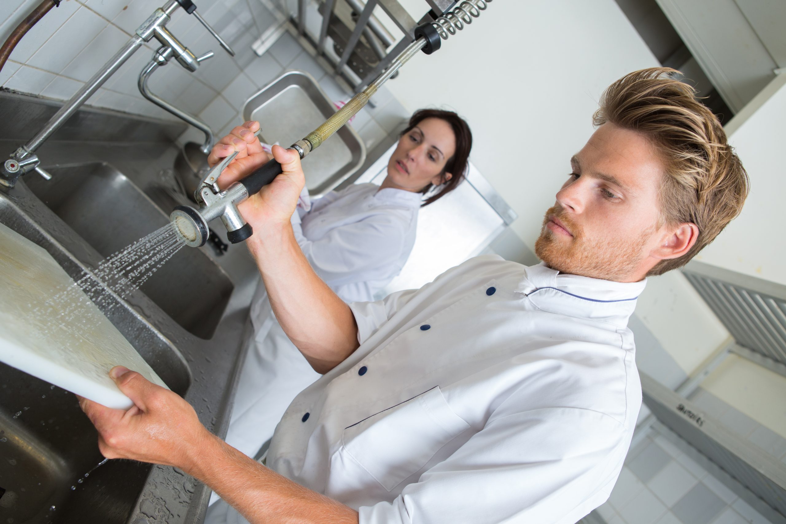 Küchenpersonal spült Geschirr in einer Restaurantküche