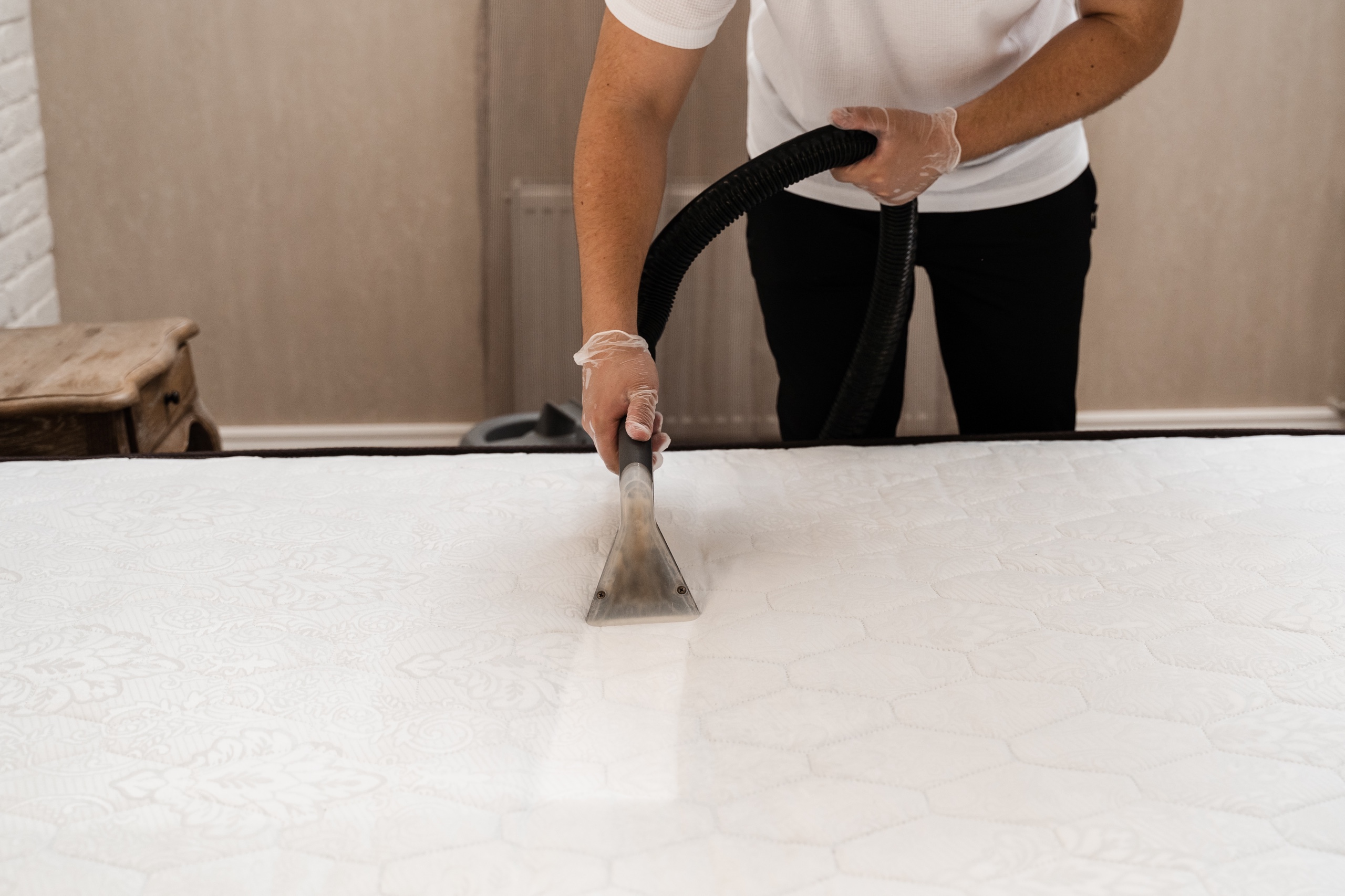 Person reinigt Matratze mit Staubsaugergerät